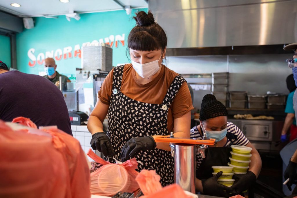 A Mexican restaurant adapts to the Covid-19 lockdown. The workers are assembling bags of orders for pick-up, take-out and delivery.